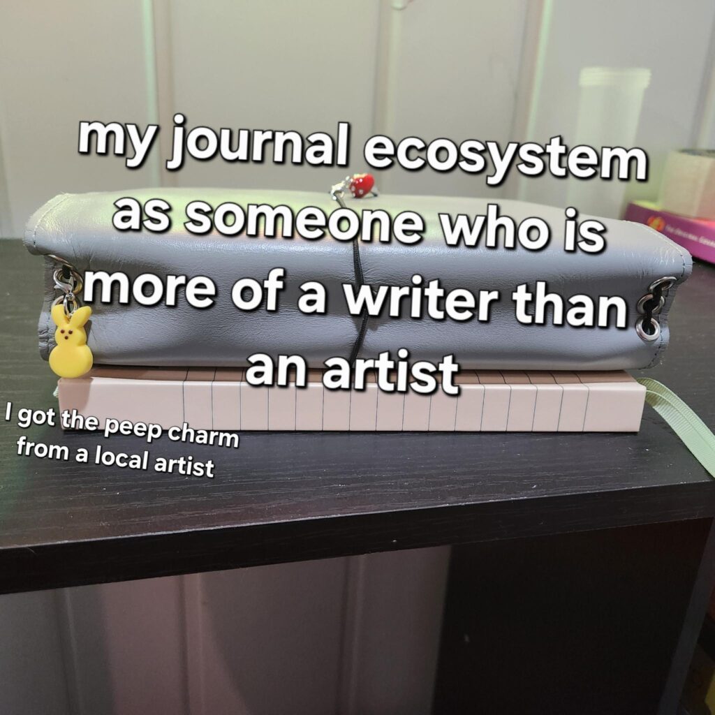 A leather journal case with a yellow peep charm hanging from the cords. Text: "my journal ecosystem as someone who is more of a writer than an artist. I got the peep charm from a local artist.
