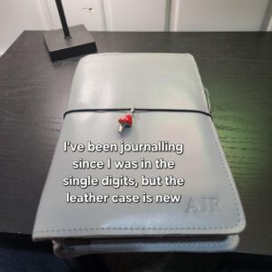 image of grey leather case with red and silver mushroom charm. Text: "I've been journalling since I was in the single digits but the leather case is new."
